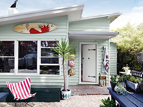 Baby Blue Beach House with pebbles and plants with nautical wooden table and white window trims